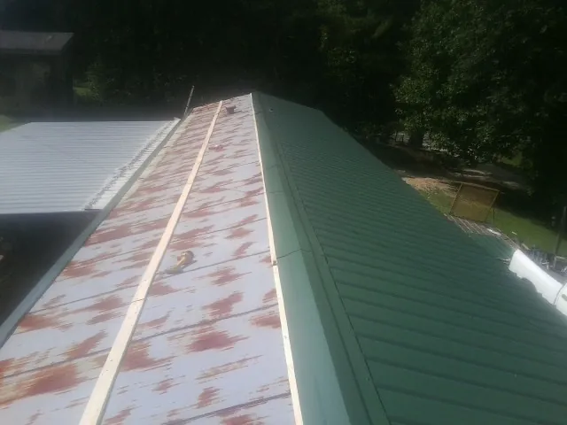 Old rusted panels beside newly installed green metal roofing — Wind Damage Roof Repair by Roofing Brothers in Ocean Gate