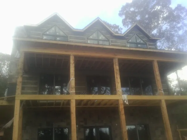 Dormers and porch framing on a large log home under construction — Roof Coating work by our crew in Ocean Gate