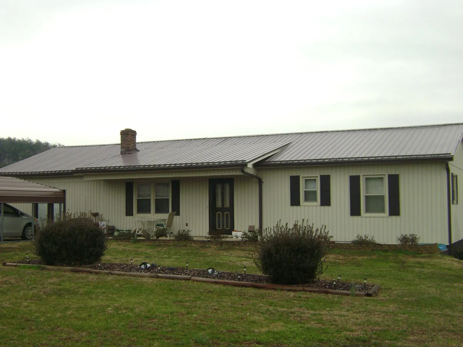 Brown metal roof on a cream sided ranch home with a brick chimney in Ocean Gate